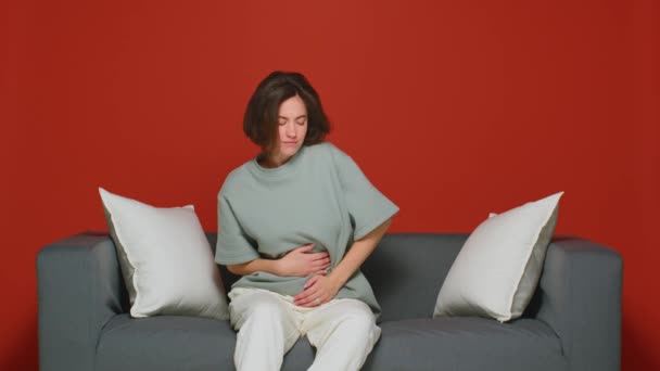 Schmerzsyndrom während der Menstruation. Ungesunde junge Mädchen berühren Bauch fühlen Bauchschmerzen, liegend auf Sofa — Stockvideo