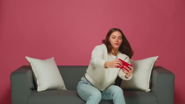 Vtipné emocionální mladá žena hraje online hry pomocí aplikace mobilního telefonu, sedí na pohovce. Technika a zábava — Stock video