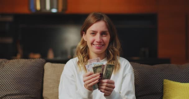 Jovem feliz contando dinheiro em dinheiro salário sentado no sofá em casa. Sucesso financeiro, conceito de dia de pagamento — Vídeo de Stock