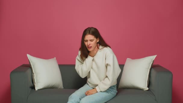 Dolor de garganta. Una mujer enferma tosiendo sufriendo síntomas de resfriado, tiene gripe, sentada en el sofá. Enfermedad por coronavirus de Omicron — Vídeos de Stock