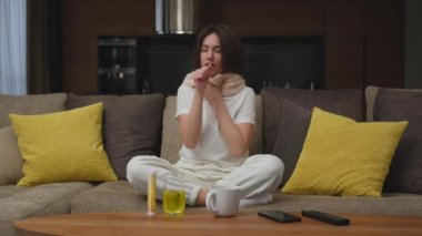 Genç bir kadın kanepede oturup öksürerek ağzı ağızla kapatıyor, soğuk algınlığı veya kronik bronşit geçiriyor. Yüksek kalite 4k görüntü