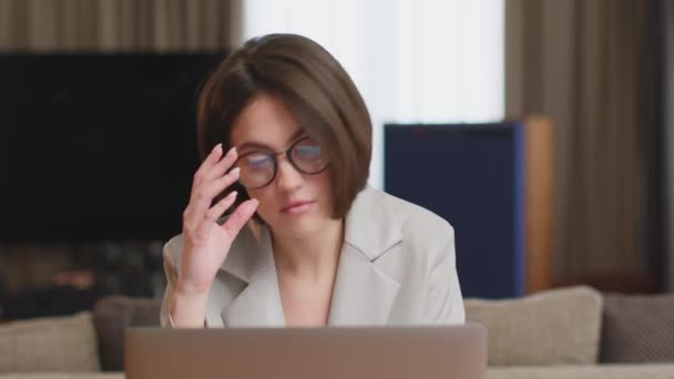 Müde junge Frau mit Brille spürt Augenmüdigkeit, reibt sich Nasenrücken, leidet Augenschmerzen nach langer Arbeit am Laptop — Stockvideo