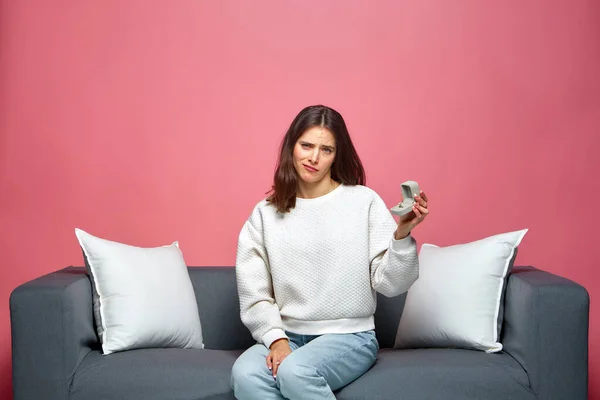 Upset young woman hold engagement ring received marriage proposal, grimacing, sitting on couch Royalty Free Stock Images