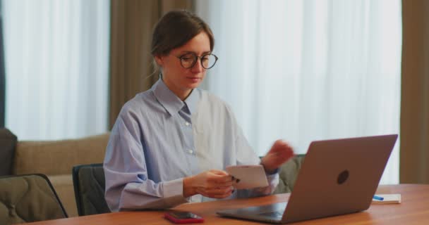 Könyvelő nő, aki számlákat vagy adókat számol, telefonnal és laptoppal kezeli a pénzügyeket az asztalnál — Stock videók