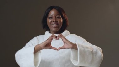Sevecen gülümseyen Afro-Amerikan kadın kalp hareketi gösteriyor. Şöyle dokun. Sadaka ve bağış. ProRes kodlayıcısı