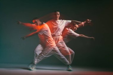 Dans eden genç kız, etkileyici hip hop dansında hareket ediyor. Kırmızı Stüdyo Işıklı Dansçı. Uzun pozlama. Breakdance okulu reklamı