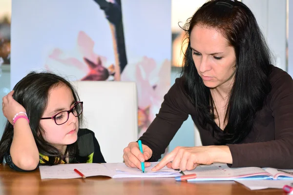 Mère aidant fille à faire des devoirs — Photo