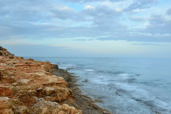 Rocky coast on sunset on a cloudy evening — Stock Photo, Image