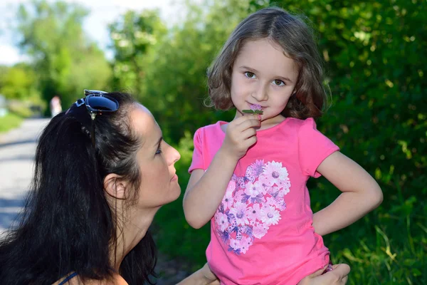 Klein meisje ruiken een bloem — Stockfoto