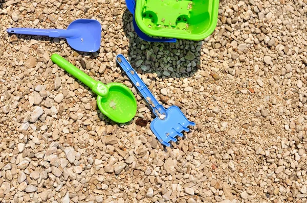 Bucket, spade and shovel on the pebbly beach — Stock Photo, Image