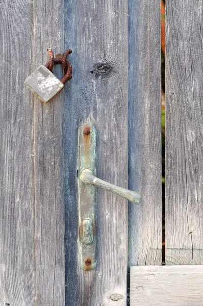 Closeup of an old wooden door with a closed padlock — Stock Photo, Image