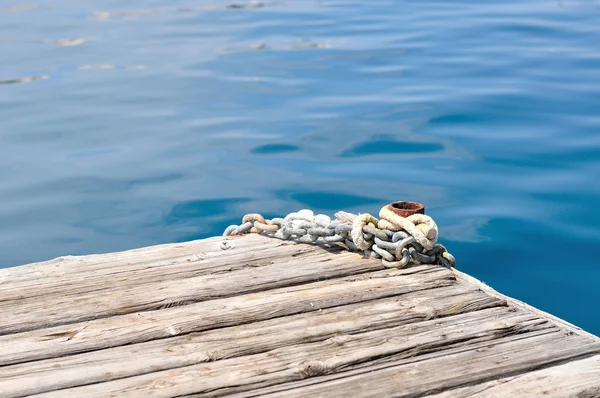 Metal ship chains and bollard on wooden pier — Stock Photo, Image