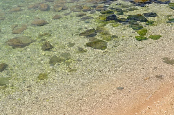 Pláž s kameny a křišťálově čistou vodou — Stock fotografie