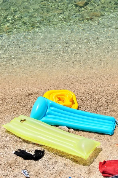 Camas flutuantes coloridas com itens de praia na praia de seixos — Fotografia de Stock