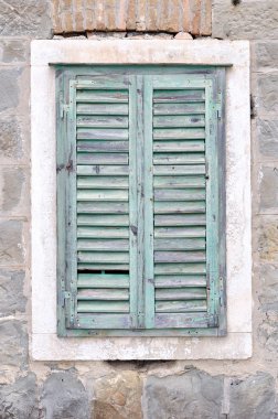 Old window with blue closed shutters on an old house