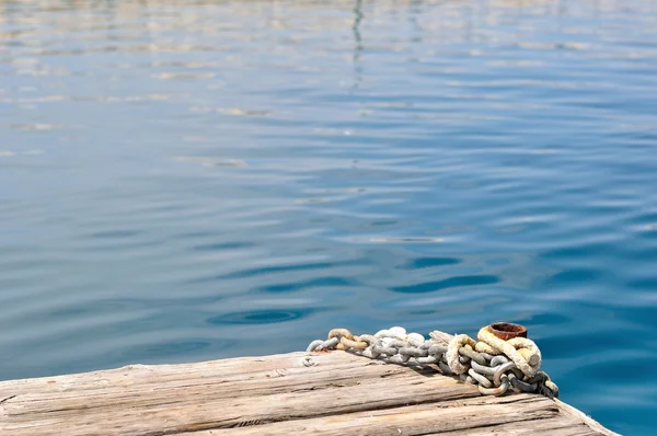 Metal chains and mooring bollard on wooden pier — Stock Photo, Image