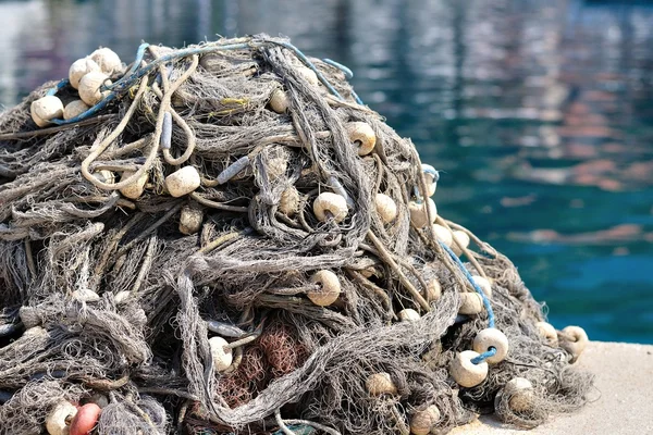 Mucchio di reti da pesca con galleggianti su una banchina — Foto Stock