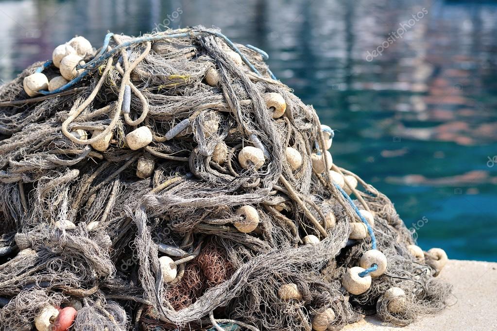 Pile of fishing nets with floats on a quay — Stock Photo © kviktor