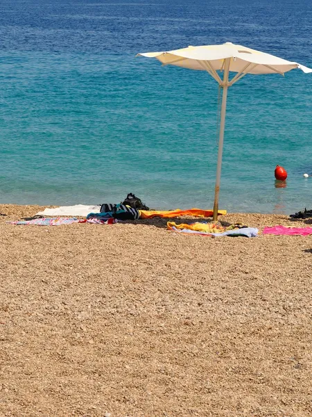 Spiaggia con ciottoli e ombrellone in una giornata estiva — Foto Stock
