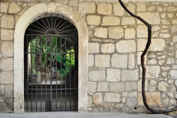 Puerta de hierro medieval en antigua pared de piedra — Foto de Stock