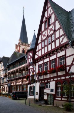 Historic buildings on a cobblestone road in Bacharach, Germany with St. Peter Kirche in the background.