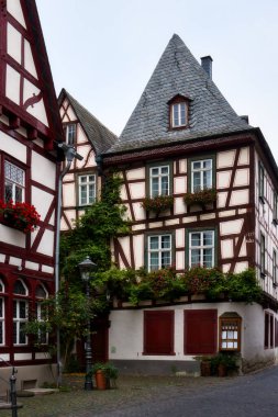 Old,  historic half-timbered building with flowers in window boxes in Bacharach, Germany on a cloudy fall day.