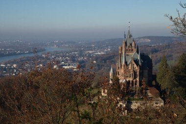 Konigswinter, Almanya - 28 Kasım 2020: Almanya 'da sisli bir sonbahar gününde şehre ve Ren nehrine bakan bir tepenin üzerindeki Drachenburg kalesi.