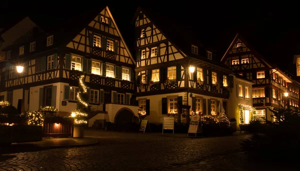 Gengenbach, Germany - December 13, 2020: Half-timbered houses with windows lit up at night on a cobblestone street during lockdown on a fall night in Gengenbach, Germany.