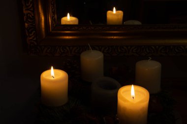 Karanlıkta yanan mumlar aynaya yansıyor.