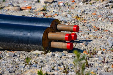 Bir inşaat sahasının üzerinde siyah yalıtılmış ısıtma borusu var.