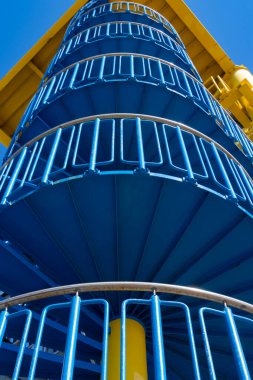 Low angle view of a blue spiral staircase with a yellow platform on top