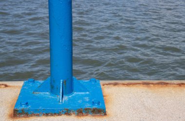 Blue pole at a dock with water in the background and copy space
