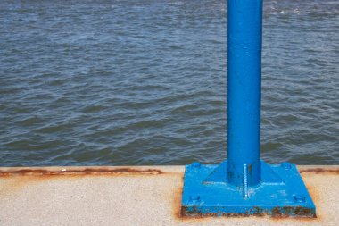 Blue pole at a dock with water in the background and copy space