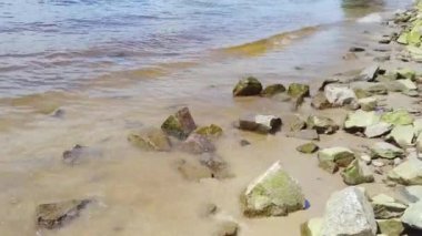 Küçük dalgalar sahilde kayalara çarpıyor. 4k video görüntülerini kapat