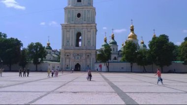 KYIV, UKRAINE - 23 Temmuz 2021: Aziz Sophia Katedrali yakınlarında çan kulesiyle yürüyen insanlar. Aydınlık yaz gününde dikey panoramik video