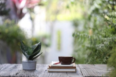 Kahverengi kahve fincanı, defter ve tahta masada yılan bitkisi.