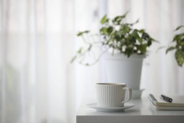 beyaz kahve fincanı ve çaydanlık beyaz masanın iç tarafında.