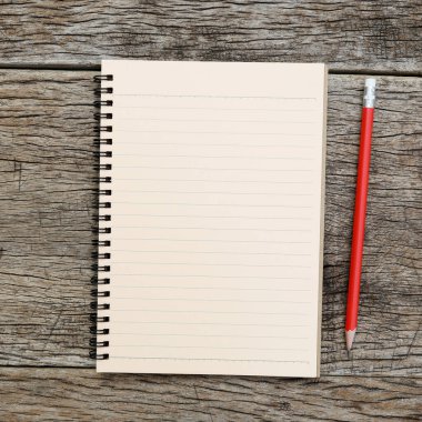 Tahta masanın üzerinde çizgileri ve kırmızı kalemi olan defter düz duruyordu.
