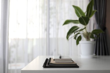 Not defterleri ve kalem beyaz masada, Aglaonema saksısıyla birlikte.