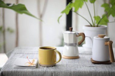 Sarı kahve fincanı ve kahve demliği ve çiçek.