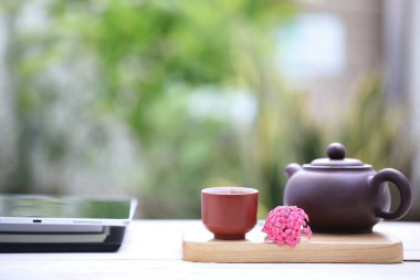 Tablet ve günlük defterli çaydanlık ve çay fincanı.