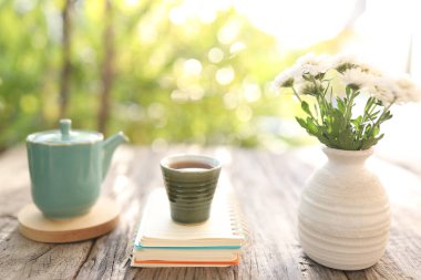 Beyaz kasımpatı vazosuyla eski bir seramik bardak ve çay demliği.