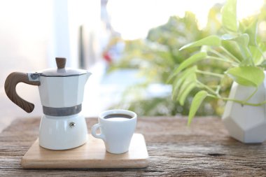 Ahşap masada beyaz fincan ve moka çömlek.