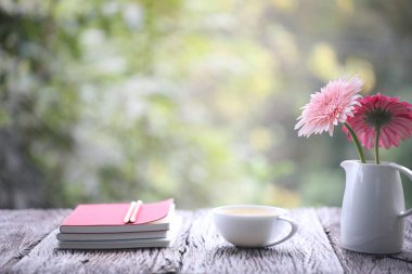 Çay fincanı, çiçekler ve defterler.