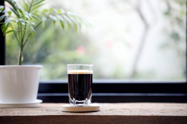 Espresso in a glass cup and small Bamboo palm plant pot