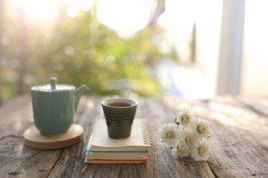 Beyaz kasımpatı vazosuyla eski bir seramik bardak ve çay demliği.