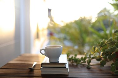 Small cup of coffee and notebooks and plant on wooden table