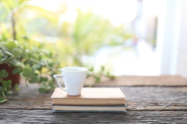 Small cup of coffee and notebooks and plant on wooden table