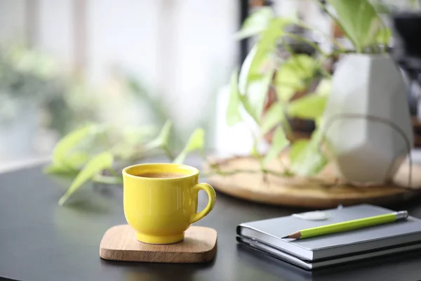 Yellow coffee cup and notebook and plant pot