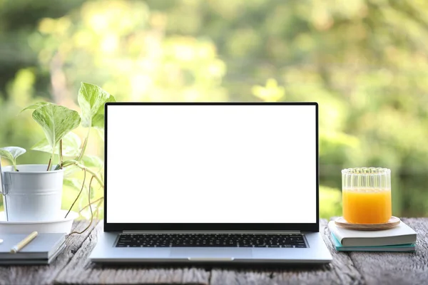 Laptop front view and mango juice with notebooks on brown wooden table outdoor